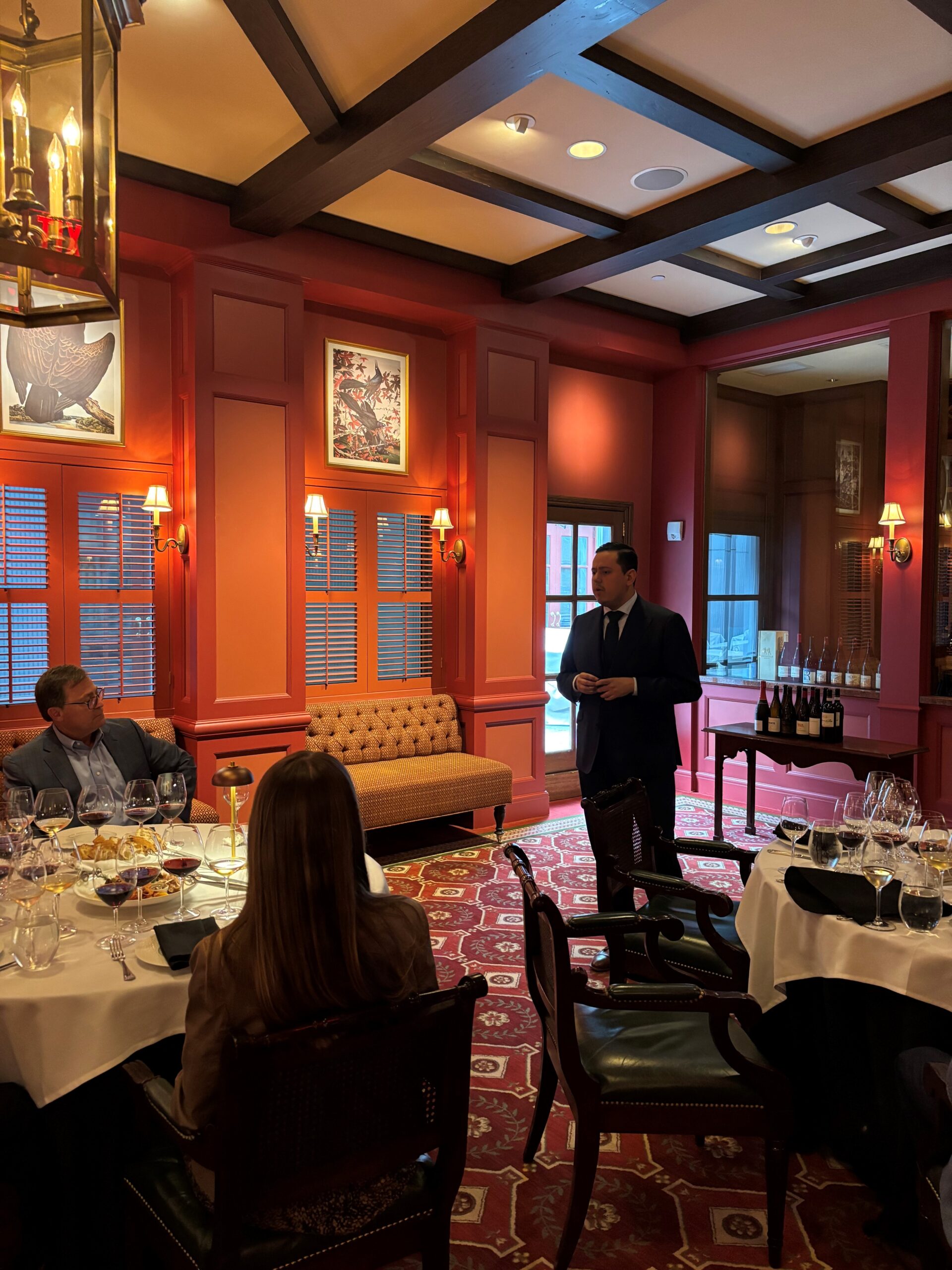 Sommelier guiding West Mermis team through wine tasting in Houston.